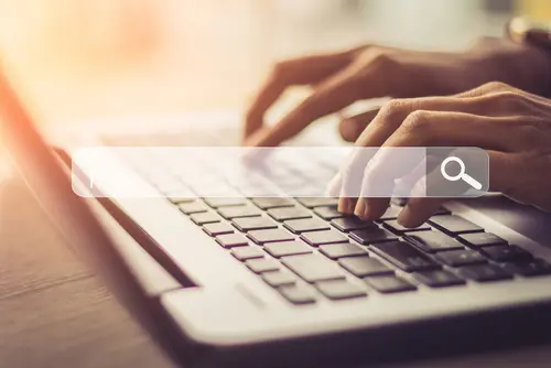 the hands of a person typing at a laptop.