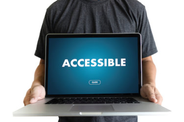 A man holds an open laptop.  On the screen the word "Accessible." 