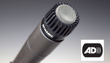 A microphone pointing up and to the right. The letters AD that indicate audio description appear on the the bottom right.