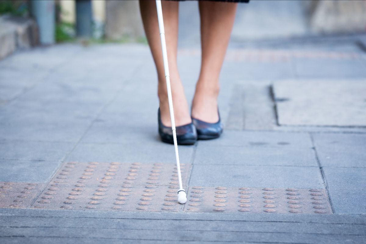 a woman in heels dragging a white cane thourgh the streets
