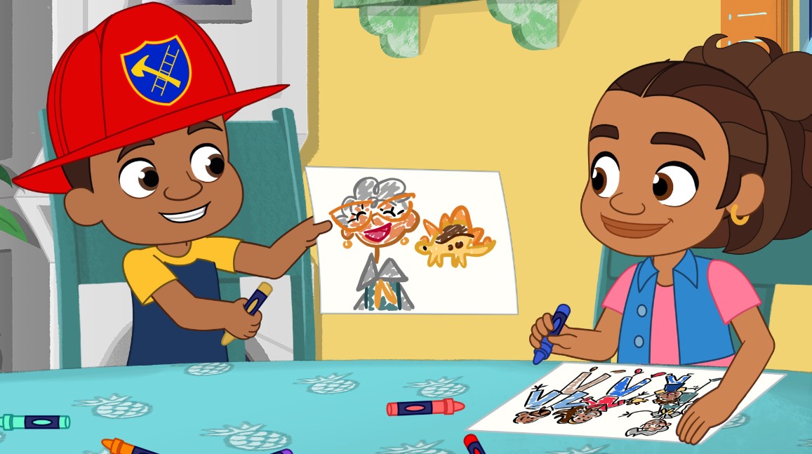 A boy holds a crayon and shows Alma a drawing on a piece of paper. The drawing shows a lady with short, curly, gray hair smiling and, next to her, a small dinosaur.