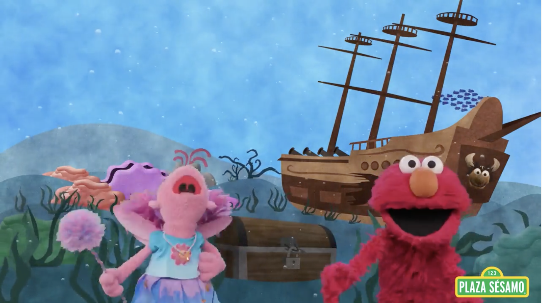 Sesame Street characters: Elmo and Abby Cadabby singing in a seascape, with a sunken ship, a treasure chest, and seaweed and corals visible in the background.