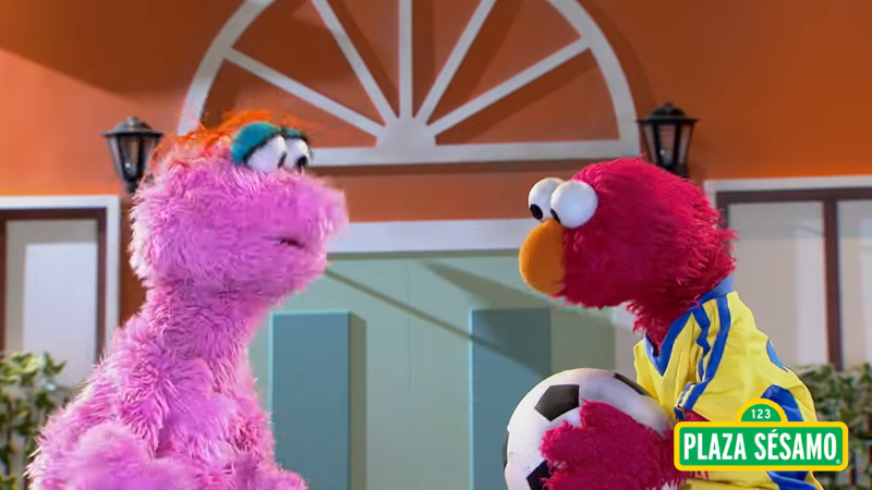 Lola and Elmo are together, with Elmo holding a soccer ball.