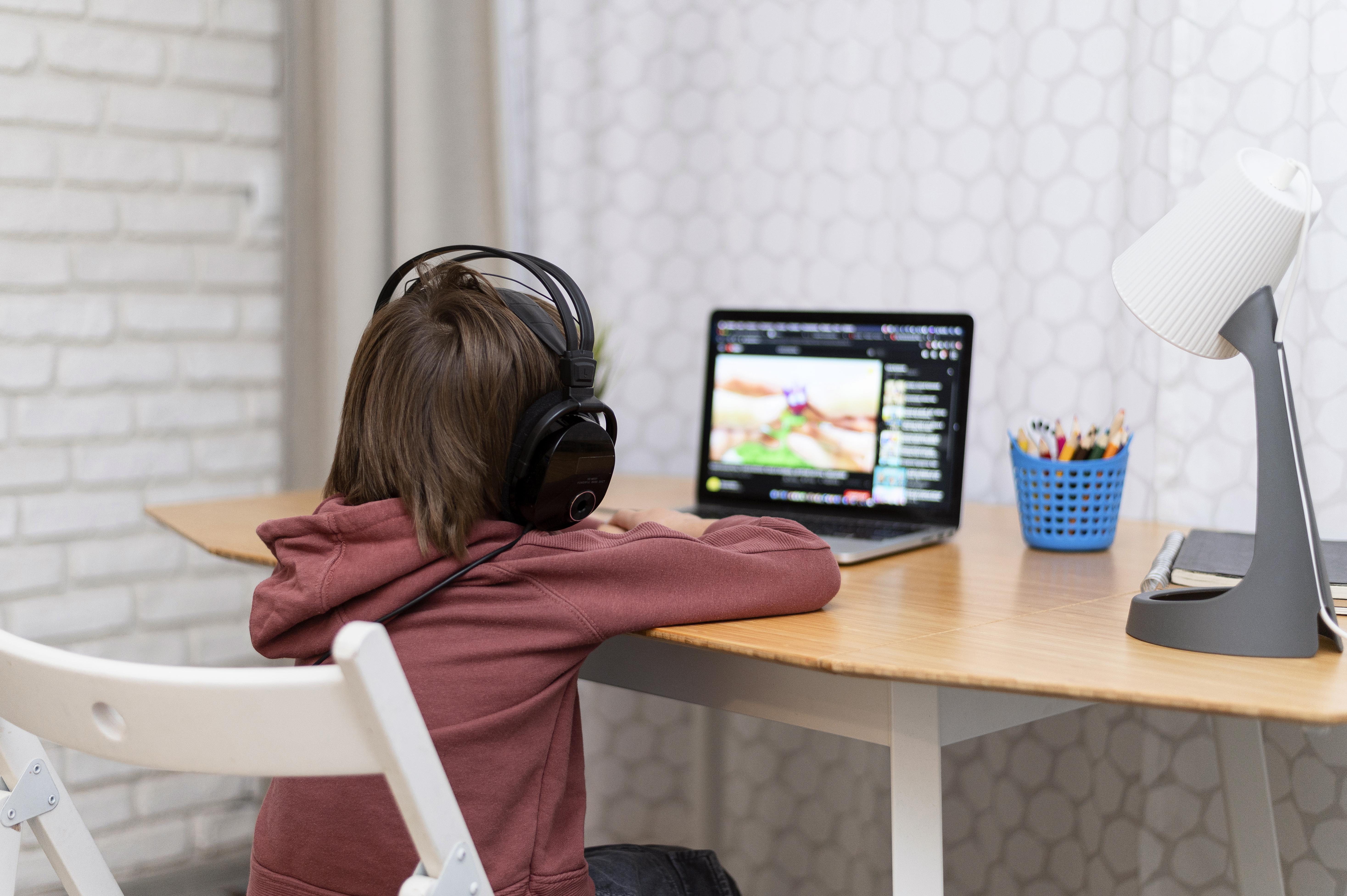 kid using laptop and wearing headphones